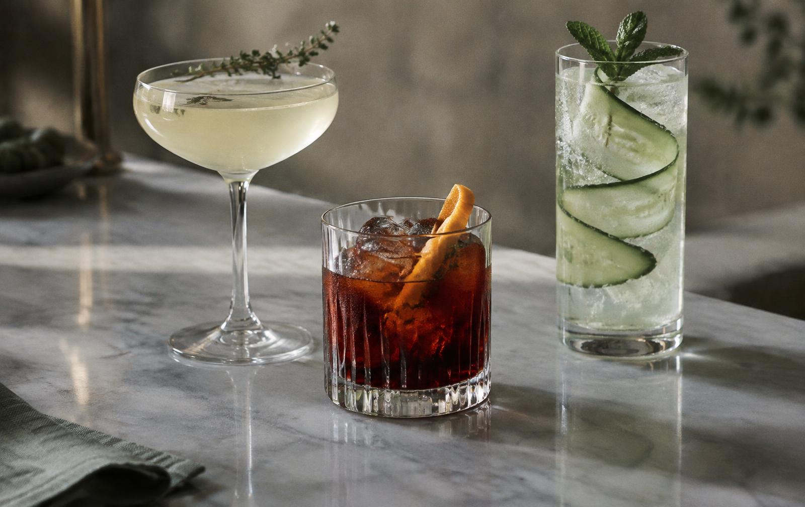 Three alcohol-free serves in a coupe, a tumbler and a highball glass on a marble bar