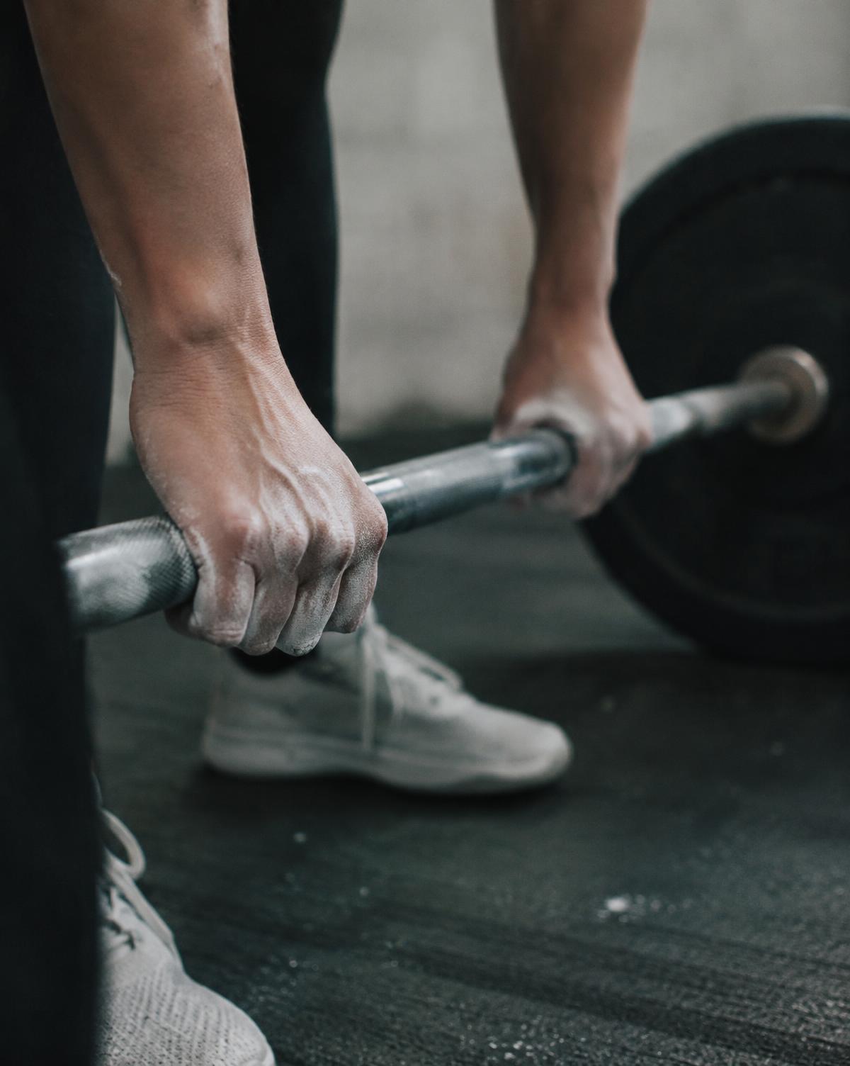 Chalked hands gripping a barbell before a lift